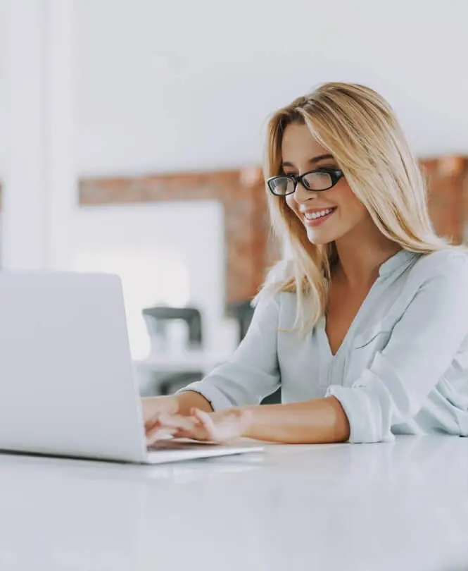 A woman at a desk in front of a laptop.