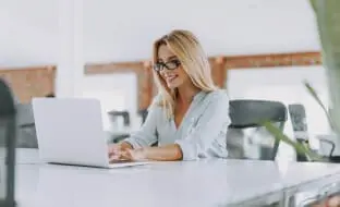 A woman at a desk in front of a laptop.