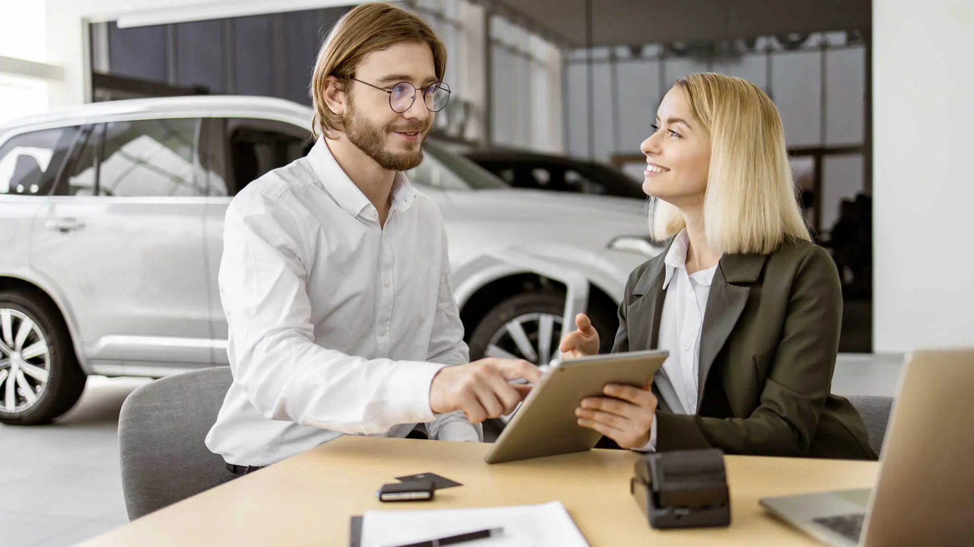 Motorist with insurance consultant sign a policy at the desk with a tablet