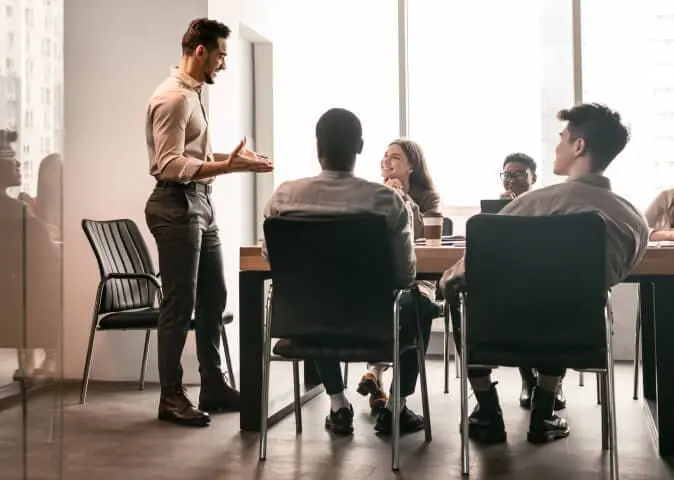 In a meeting room a team leader speaks to colleagues