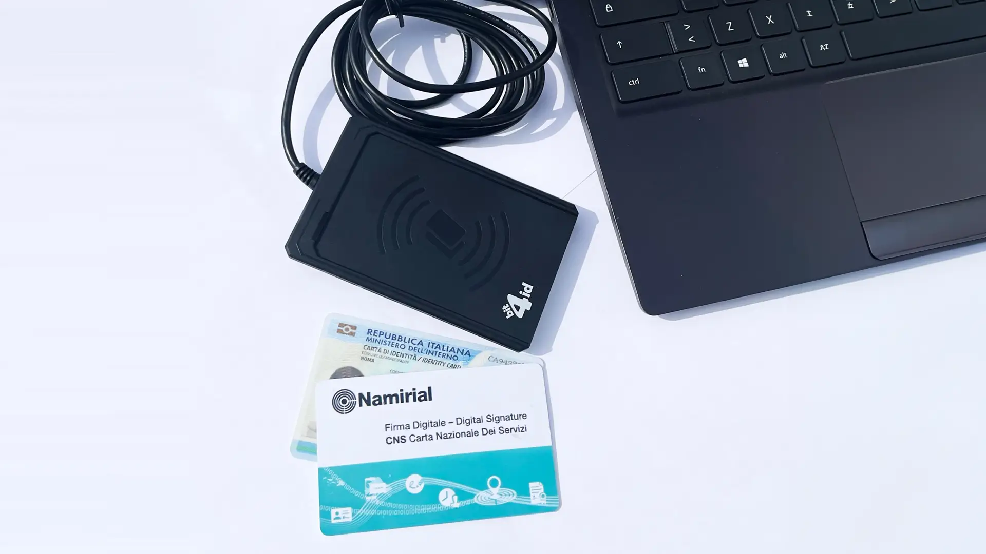 A smart card reader connected to a laptop close to some smart cards