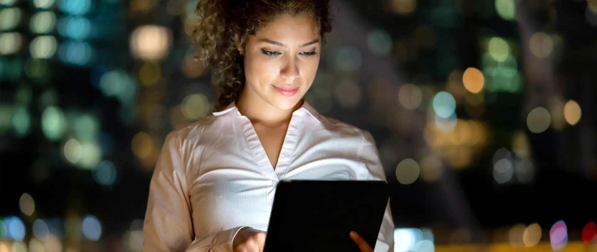 Donna che tiene in mano un tablet e guarda lo schermo sorridendo.