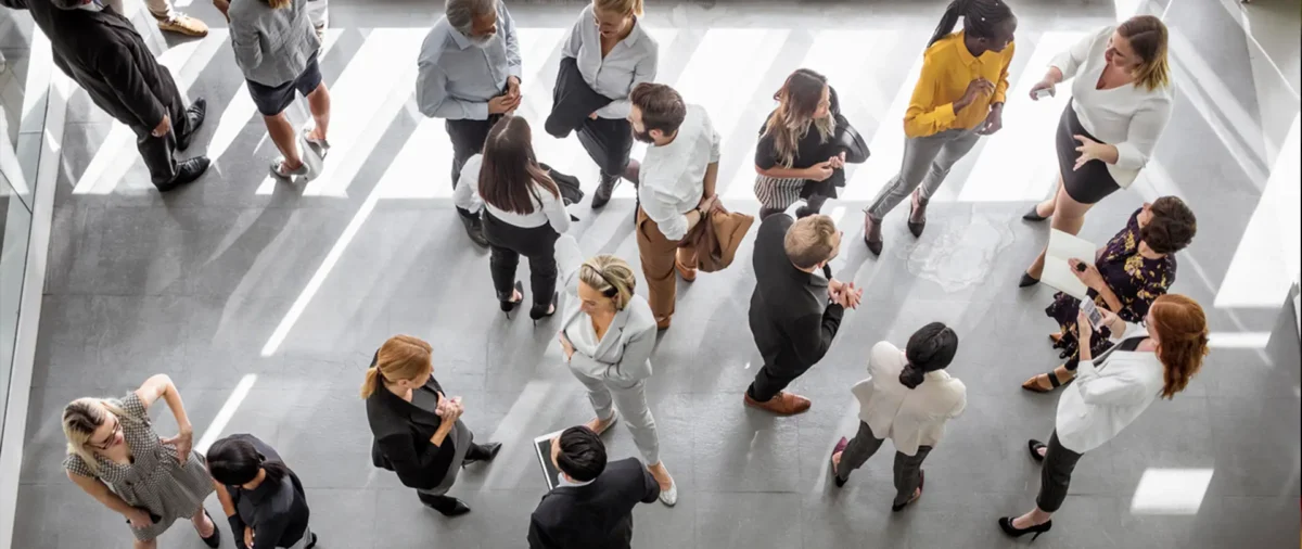 Group of men and women in professional attire seen from above talking to each other.