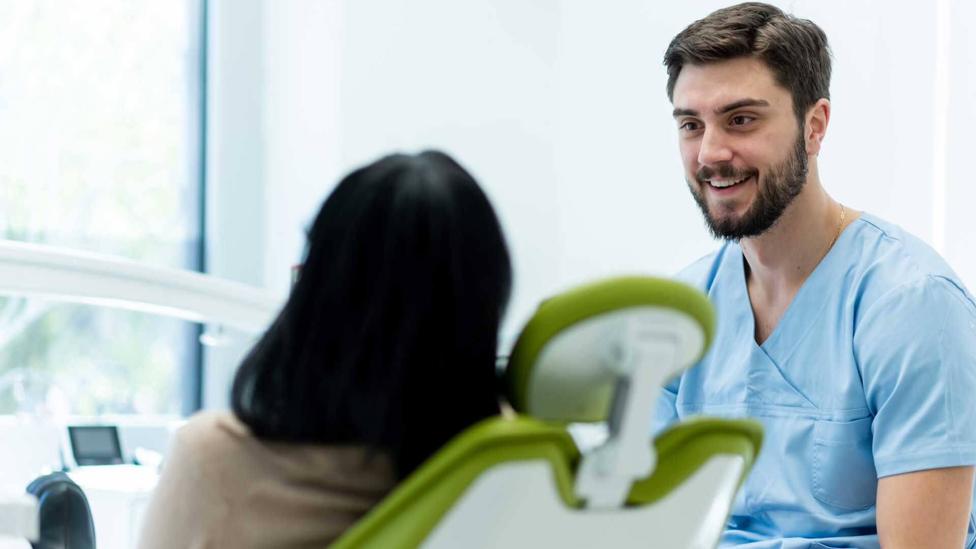Dentista con camice con una paziente su una sedia odontoiatrica
