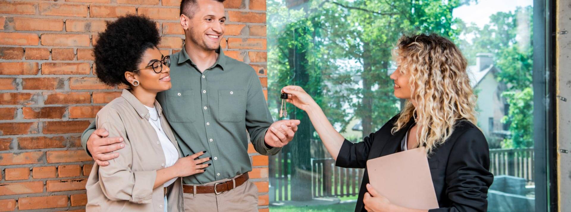 A couple receives the keys to their house from a real estate agent.