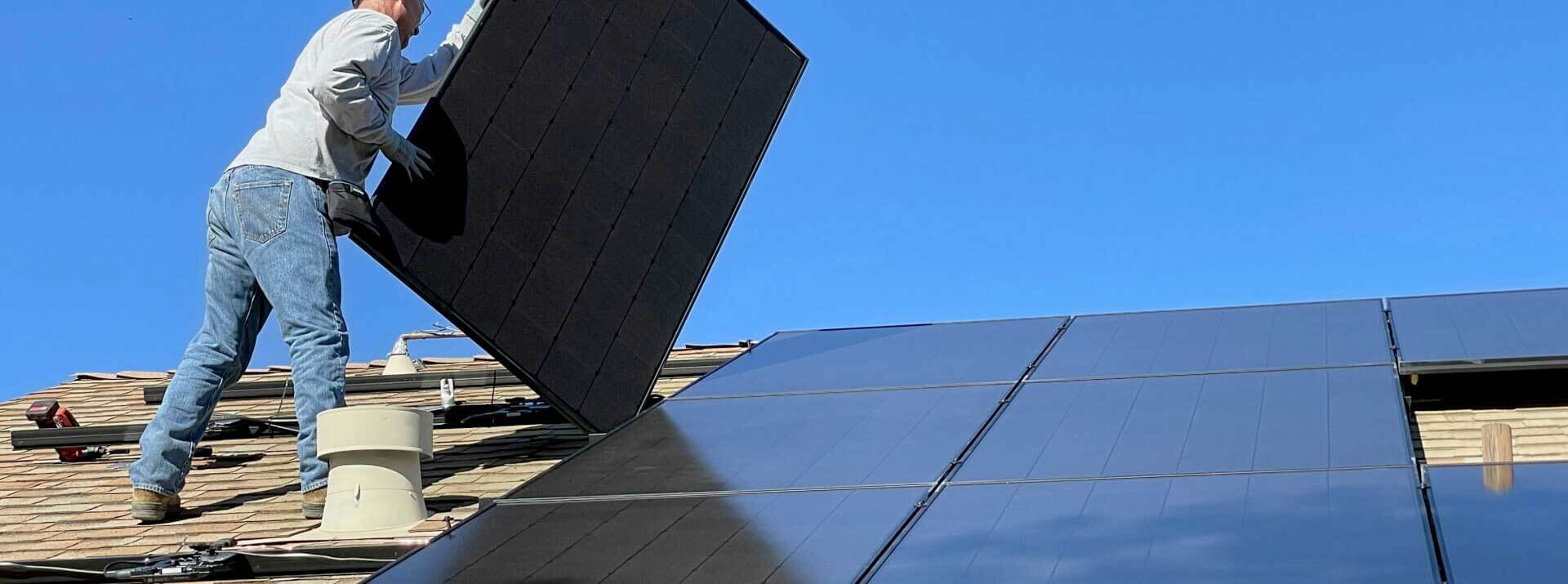 Un installatore su un tetto monta un pannello fotovoltaico