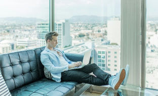 Un uomo seduto su un divano usa un laptop sentendosi sicuro per la conservazione dei dati sensibili
