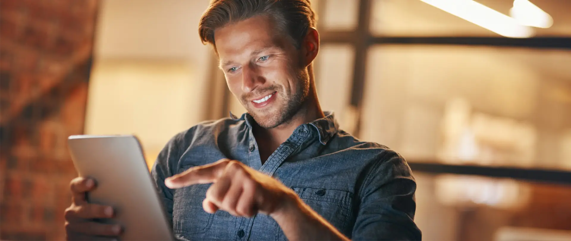 Man holding a tablet and pointing his finger at the screen while smiling.