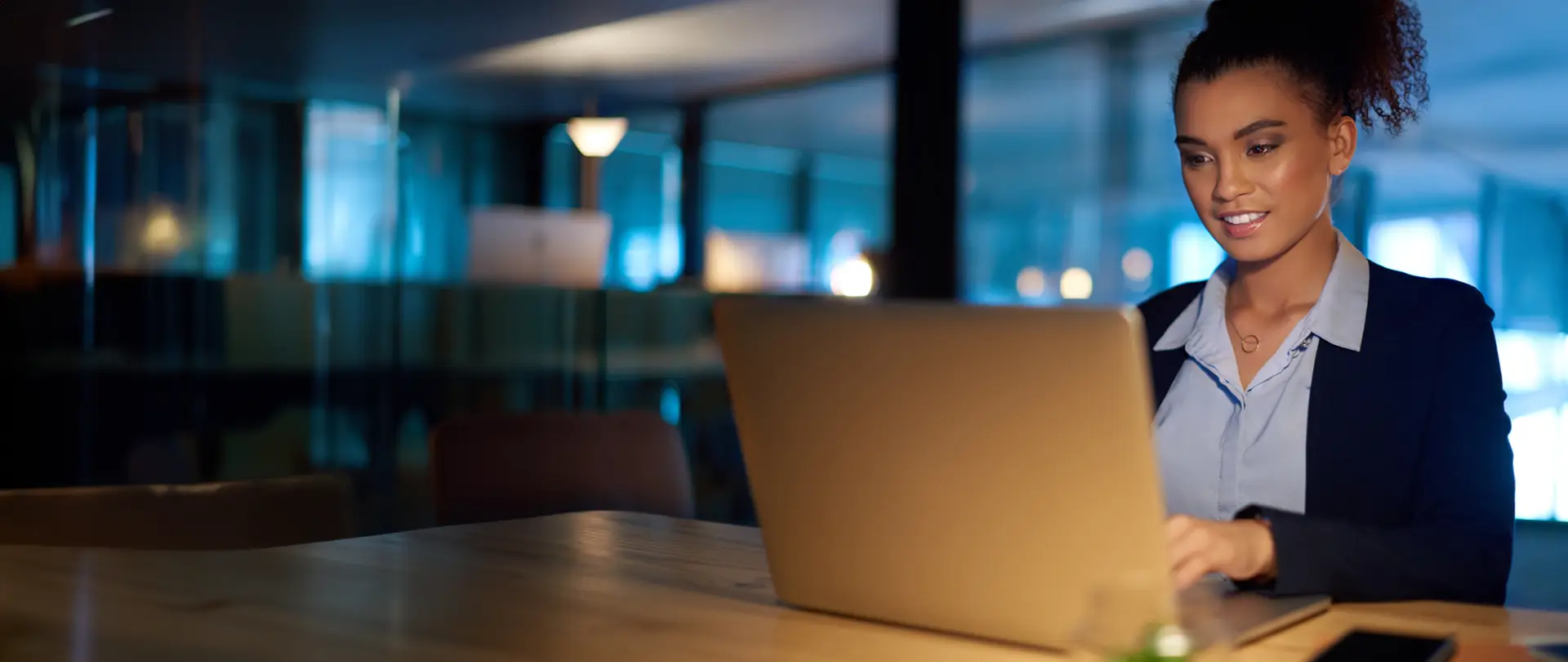 Woman at a desk working on her personal computer smiling.